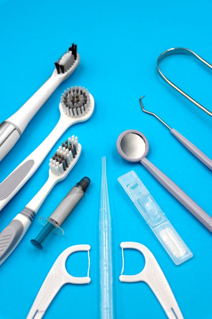 Services-02 A flat lay of various dental care tools including toothbrush, floss, and dental pick on blue background.