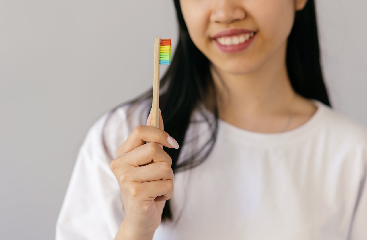 creative Smiling woman holding a rainbow-colored bamboo toothbrush, promoting dental hygiene and inclusivity.